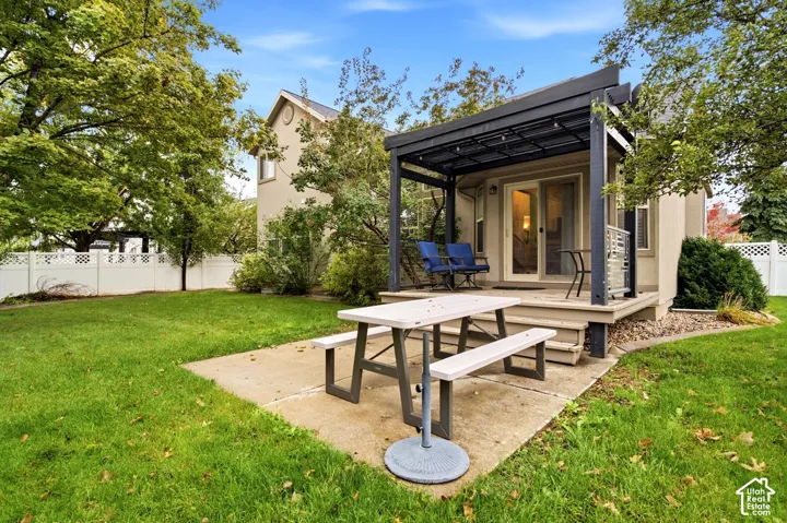 Private backyard featuring a concrete patio, a covered pergola, mature trees, and vinyl perimeter fencing