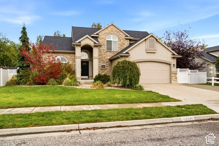 Stone veneer exterior with arched entryway, multi-gabled roofline, and attached two-car garage