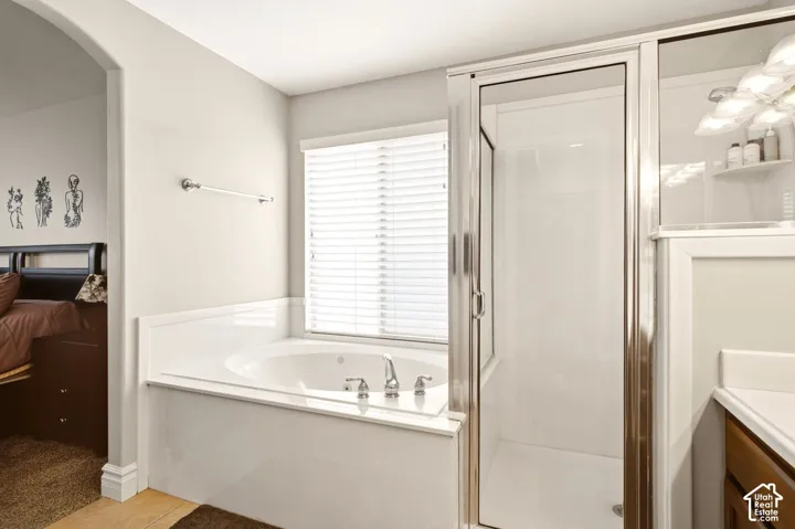 Oval soaking tub with a white surround, glass-enclosed shower, polished chrome fixtures, and horizontal window blinds