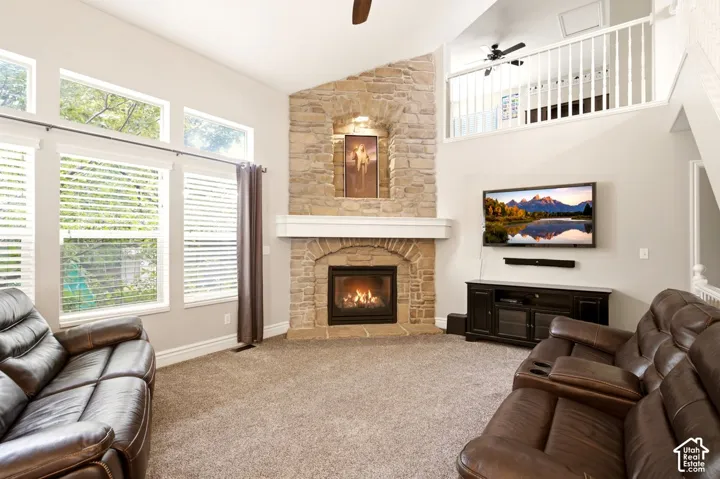 Vaulted ceilings, full-height stone fireplace with a custom mantle, recessed wall niche, multi-pane windows, and interior balcony with a white railing