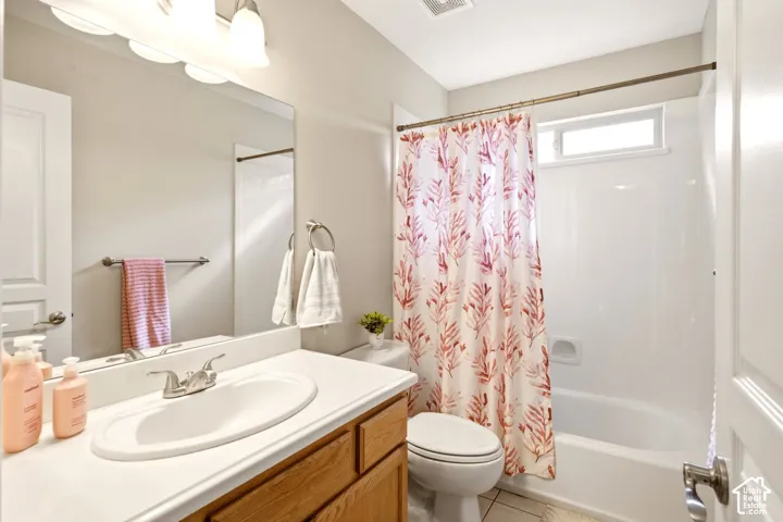 Bathroom featuring a wood vanity, solid-surface countertop with an integrated oval sink, chrome dual-handle faucet, large wall-mounted mirror, and a tub-shower combination with a transom window