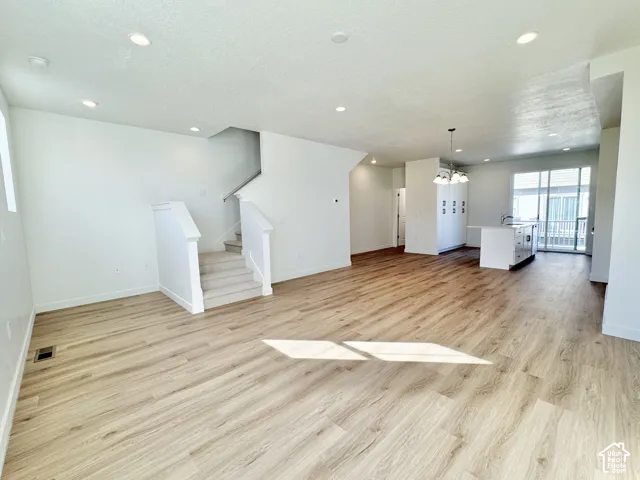 Open-concept interior featuring wood-finish flooring, recessed lighting, a kitchen island, carpeted stairs, and sliding glass doors