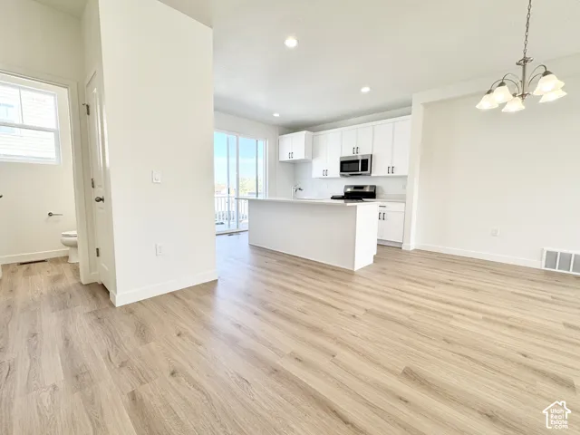 Open-concept kitchen featuring white cabinetry, a center island with a breakfast bar, recessed lighting, and wood-finish flooring