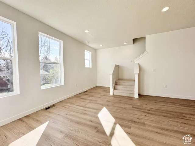 Interior space featuring wood-finish flooring, recessed lighting, multiple windows, and a carpeted staircase with white balusters
