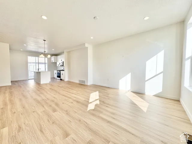 Open-concept interior featuring wood-finish flooring, recessed lighting, and a kitchen island with white cabinetry