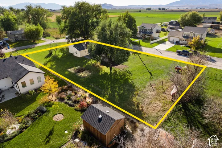 Expansive parcel featuring mature trees, manicured lawn areas, a dedicated storage shed with a shingle roof, and mountain range scenery