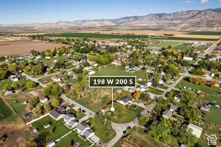 Aerial perspective featuring a residential lot with mature trees and a prominent mountain range backdrop