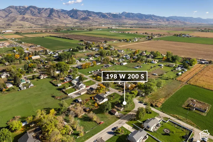 Aerial perspective of the property featuring surrounding agricultural land, expansive open space, and prominent mountain range backdrop