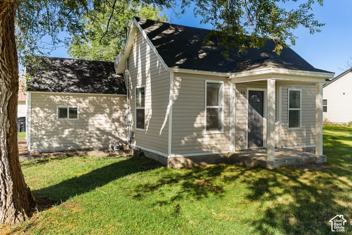 Exterior featuring tan horizontal siding, asphalt shingle roofing, and a covered front porch with support columns