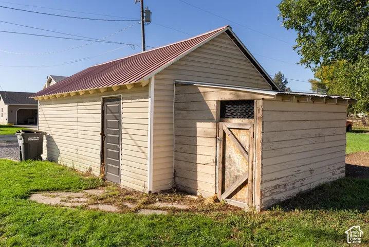 Detached garage featuring metal roofing, vinyl siding, and an attached storage enclosure