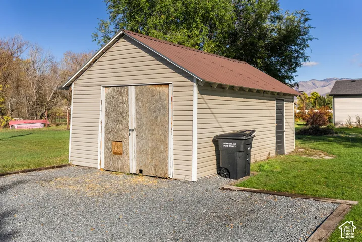 Detached garage featuring vinyl siding, a gabled roof with asphalt shingles, and double-door entry