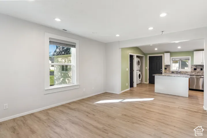 Interior space featuring wood-finish flooring, recessed lighting, and a kitchen area with white cabinetry, stone-finish countertops, and stainless steel appliances