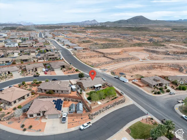 Aerial perspective of a corner lot property featuring a stone-clad perimeter wall, desert landscaping, and a mountain backdrop