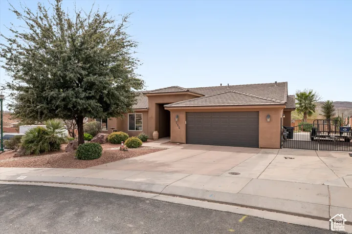 Stucco exterior with a tile roof, oversized attached garage, concrete driveway, and low-maintenance desert landscaping