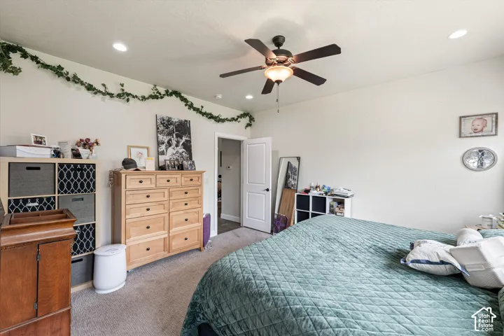 Neutral-toned room featuring neutral carpeting, a ceiling-mounted fan with integrated light fixture, recessed lighting, and a multi-panel interior door