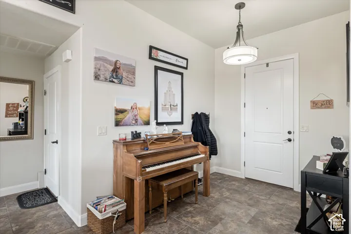 Entryway featuring neutral wall tones, tile flooring, a multi-panel door with matte black hardware, and an overhead pendant light fixture