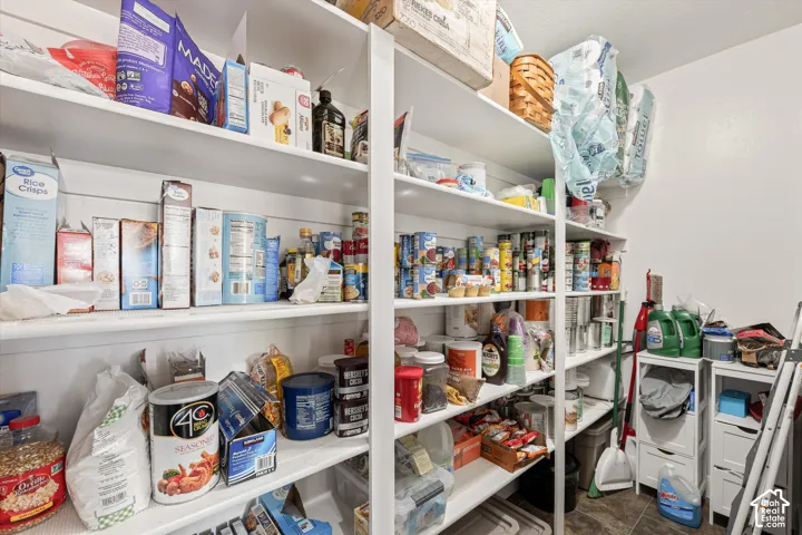 Walk-in pantry featuring white floor-to-ceiling shelving and tiled flooring