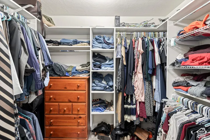 Walk-in closet featuring white built-in shelving, vertical storage compartments, and multi-level hanging rods