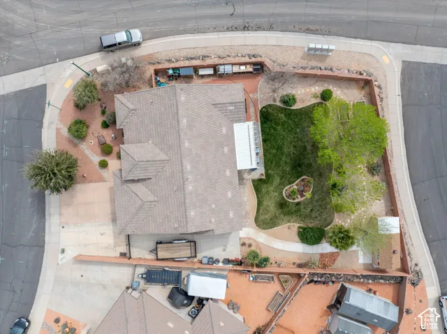 Corner lot property featuring an enclosed backyard, mature landscaping, paved walkways, and a concrete patio