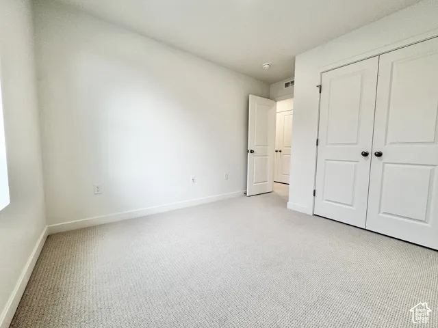 Neutral-toned wall-to-wall carpeting, double-panel closet doors, and multi-panel interior doors with dark hardware