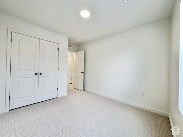 Neutral-toned carpeting, two-panel interior doors, recessed ceiling lighting, and double-door closet storage