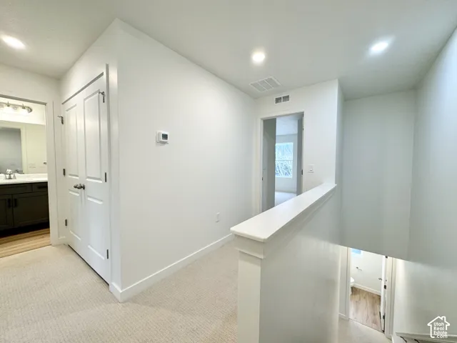 Hallway featuring neutral carpeting, recessed ceiling lighting, and solid-core interior doors