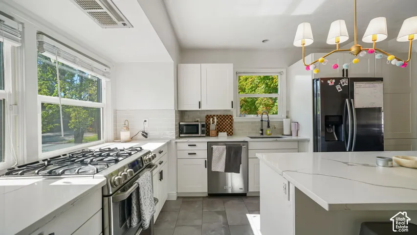 Kitchen featuring white shaker-style cabinetry, quartz countertops, subway tile backsplash, stainless steel gas range, and large center island