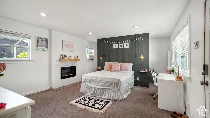 Room featuring a dark-toned paneled accent wall, built-in fireplace with a wood-finish mantel, recessed lighting, and wall-mounted light fixtures