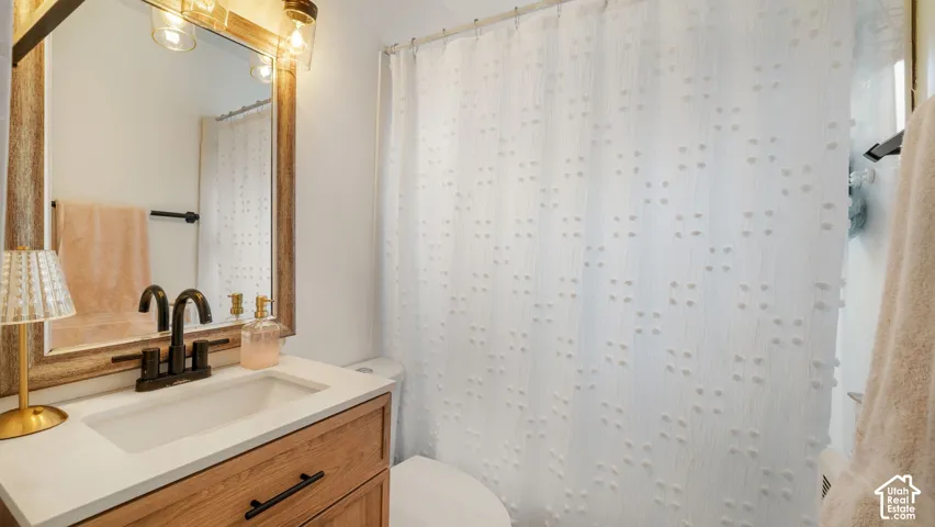 Bathroom vanity featuring a wood-finish cabinet, white countertop, integrated sink, and matte black hardware with a matching faucet