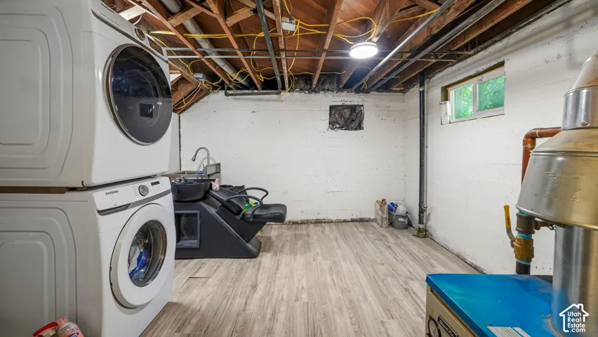 Utility space featuring wood-finish flooring, painted masonry walls, exposed ceiling joists, and a single-pane rectangular window
