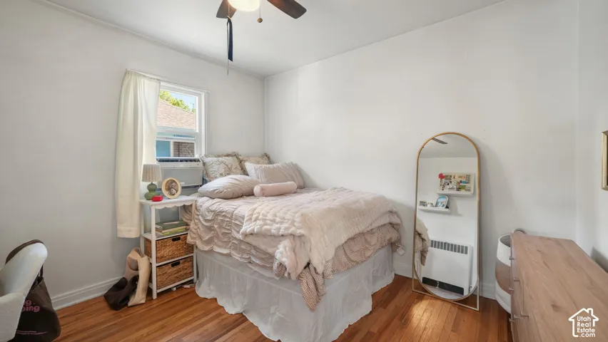 Interior space featuring wood-finish flooring, a ceiling fan with integrated light fixture, and a wall-mounted radiator