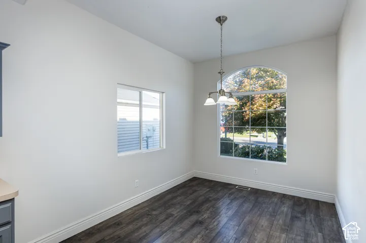 Area featuring wood-finish flooring, an arched window, a secondary sliding window, and a three-light pendant fixture