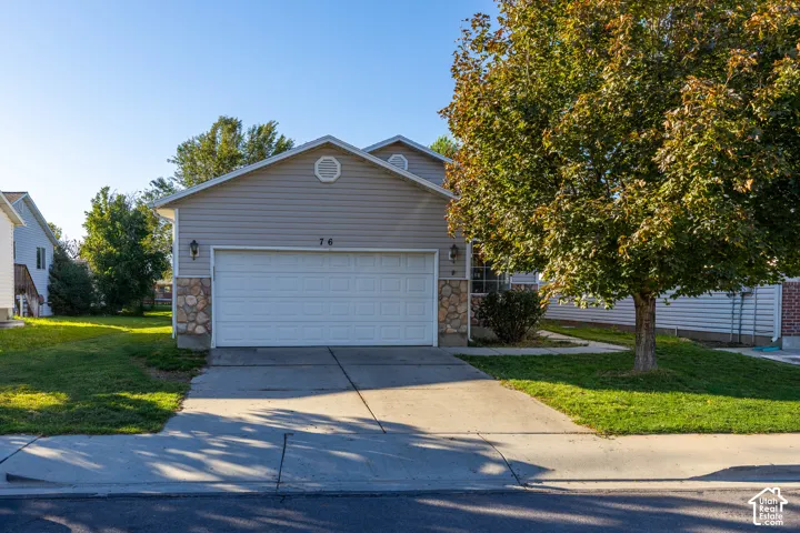 Exterior featuring light horizontal siding, stone veneer accents, a concrete driveway, and a two-car garage