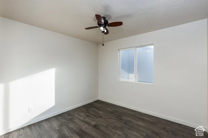 Neutral-toned interior featuring wood-finish flooring, a sliding window with white trim, and a ceiling-mounted light fixture with a five-blade fan