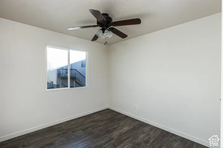 Room featuring wood-finish flooring, a neutral wall palette, and a five-blade ceiling fan with a multi-light fixture