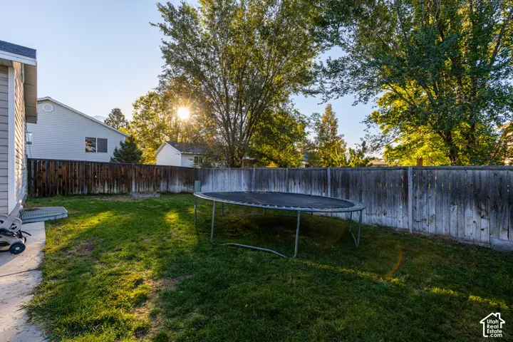 Rear yard featuring a grass lawn, perimeter wood fencing, and a concrete patio