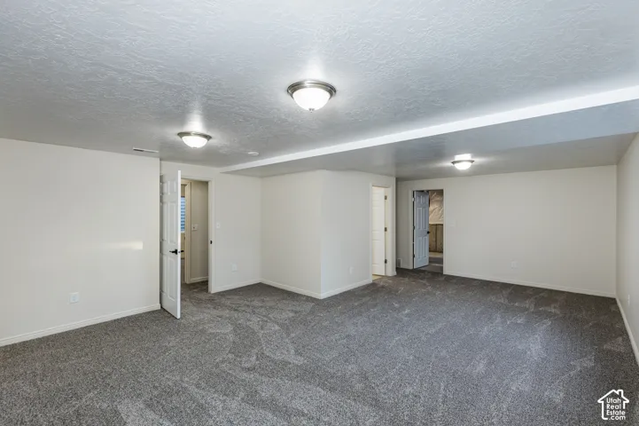 Neutral-toned interior space featuring textured carpeting, smooth walls, recessed lighting fixtures, and six-panel interior doors