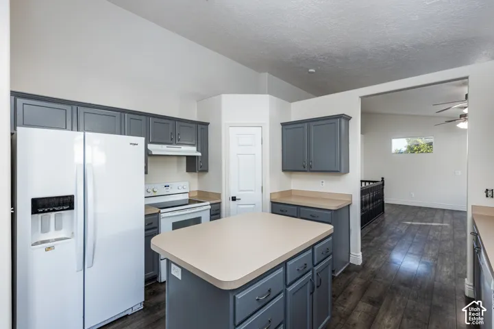 Kitchen featuring dark gray cabinetry, a center island with countertop, wood-finish flooring, and vaulted ceilings