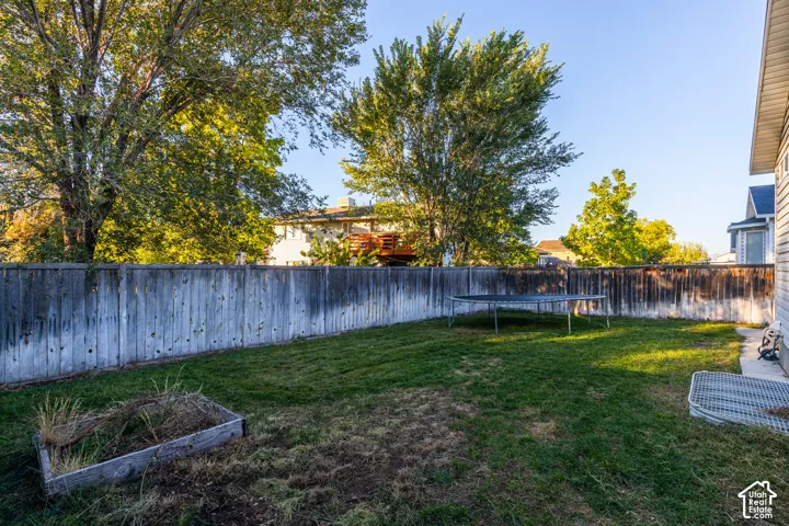 Private backyard featuring a wood fence, lawn area, and a raised garden bed