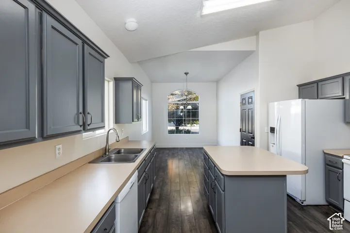 Kitchen featuring charcoal-toned cabinetry, solid-surface countertops, wood-finish flooring, a central island, and an arched window