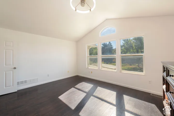 Vaulted ceilings, wood-finish flooring, triple-pane window configuration with an arched transom, and a circular geometric chandelier