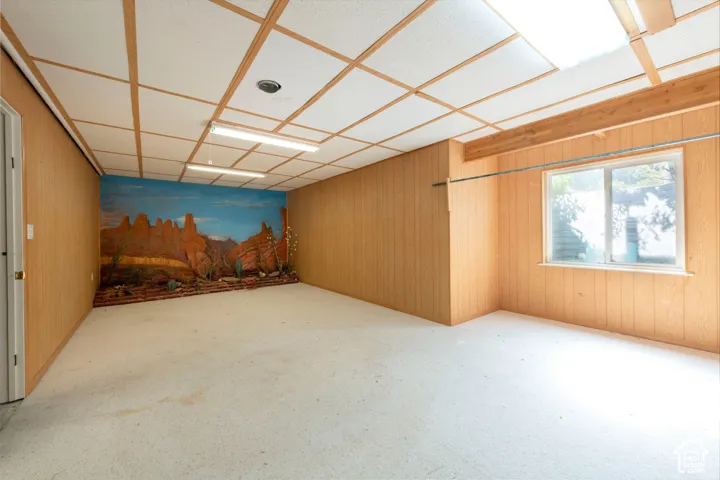 Wood-paneled interior walls, dropped ceiling with grid-work, fluorescent light fixtures, and single-pane window
