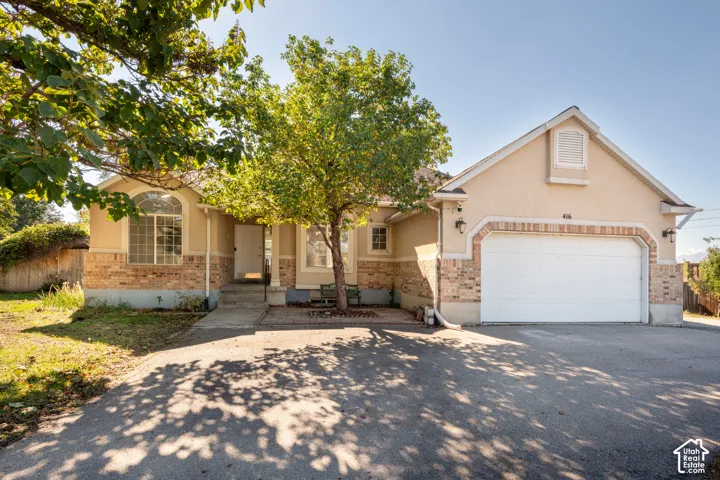 Single-story exterior featuring a stucco and brick facade, an attached two-car garage, an arched window, and concrete driveway