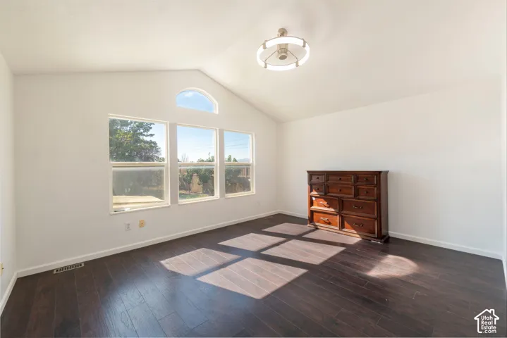 Vaulted ceilings, wood-finish flooring, three-panel window configuration with an arched transom, and a circular ceiling fixture