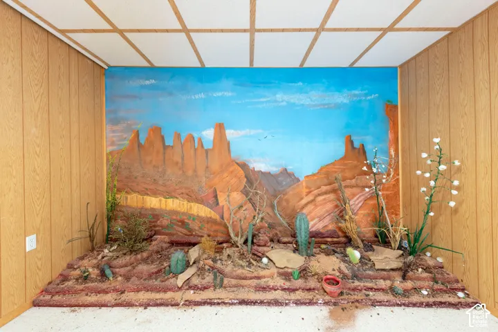 Interior space featuring wood-paneled walls, a suspended ceiling with grid framework, and a built-in floor-to-ceiling desert landscape mural