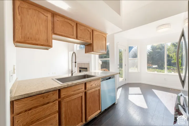 Kitchen featuring wood cabinetry, stone-finish countertops, stainless steel sink with high-arch faucet, dark wood-finish flooring, and large windows
