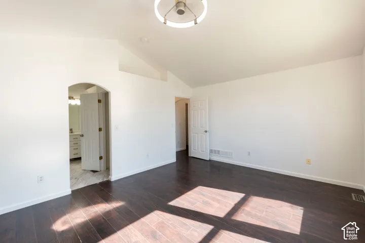 Vaulted ceilings, wood-finish flooring, circular modern overhead lighting, and an arched entry