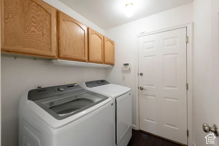 Utility room featuring natural wood-finish wall cabinetry, dark wood-finish flooring, and a six-panel exterior door with satin nickel hardware