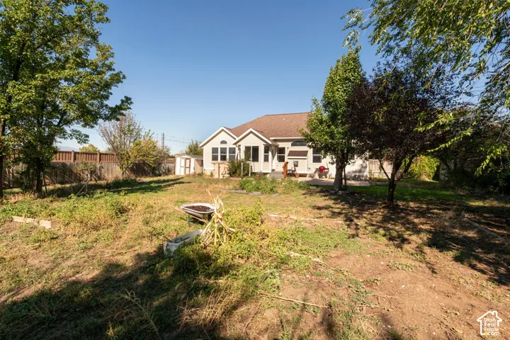 Spacious backyard featuring mature trees, wood privacy fencing, and a concrete patio