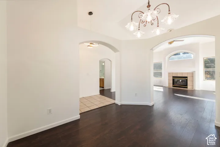 Interior area featuring arched entryways, wood-finish flooring, tile flooring, a multi-arm chandelier, and a fireplace with tile surround